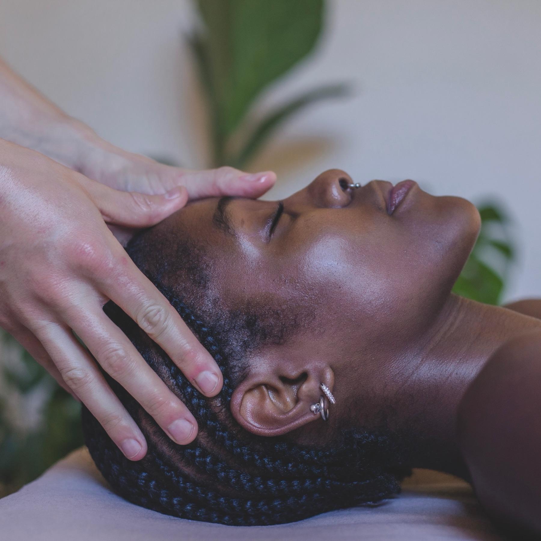 A client resting with eyes closed while a therapist cradles her head