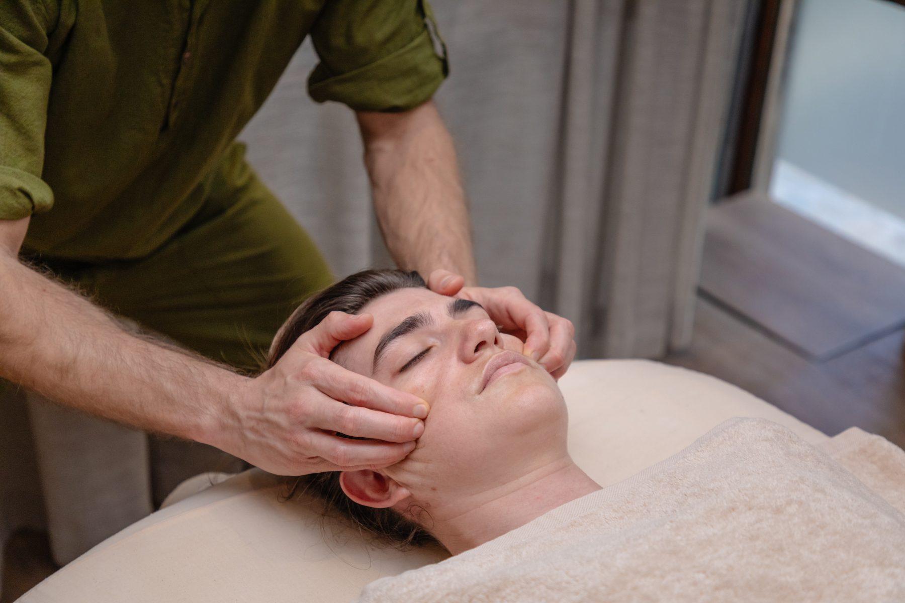 Therapist massaging a client’s face and temples